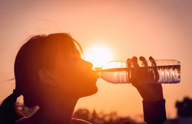 Una mujer bebe agua por las altas temperaturas.